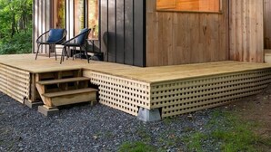 A wooden cabin with a sloped roof, a deck, and two chairs. - The Twig, Outdoor Shower, Deck, and Cozy Chimney! (Sylva)
