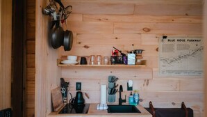 A compact kitchen with wooden cabinetry, a sink, and various utensils. A map titled "BLUE RIDGE PARKWAY" is visible on the wall. - The Twig, Outdoor Shower, Deck, and Cozy Chimney! (Sylva)