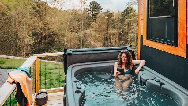 A hot tub on a wooden deck with a view of trees and hills.