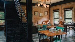 A spacious dining area with a wooden table and chairs, a staircase, and brick walls. - Pousada LaPianta  (Camanducaia)