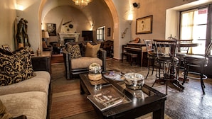 A spacious living room with a fireplace, comfortable seating, and a dining area with a piano.