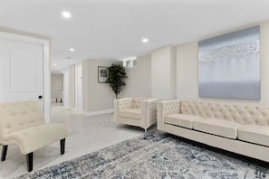 Un salon moderne avec un canapé beige, un fauteuil assorti et un tapis à motifs.