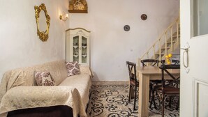 Une pièce comprenant un lit, une table à manger avec des chaises, un lustre et un escalier.