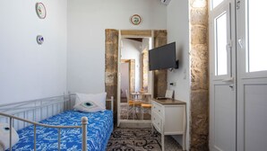 Une chambre à coucher avec un lit, un bureau, une télévision et une porte.