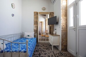 A bedroom with a bed, a desk, a television, and a door.