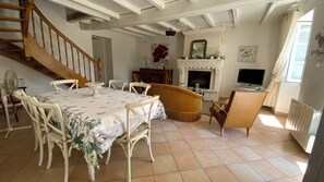 A dining area with a table set for four, a fireplace, and a television.