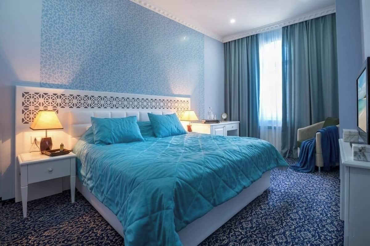 Una camera d'albergo con un letto, comodini, una lampada, una sedia e una televisione.