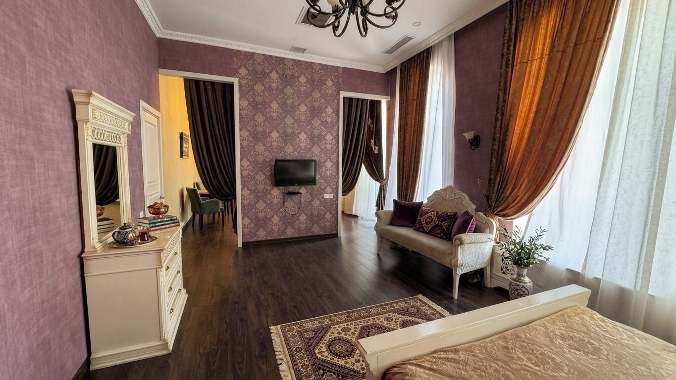 A bedroom with a bed, a dresser, a television, a sofa, and a mirror.