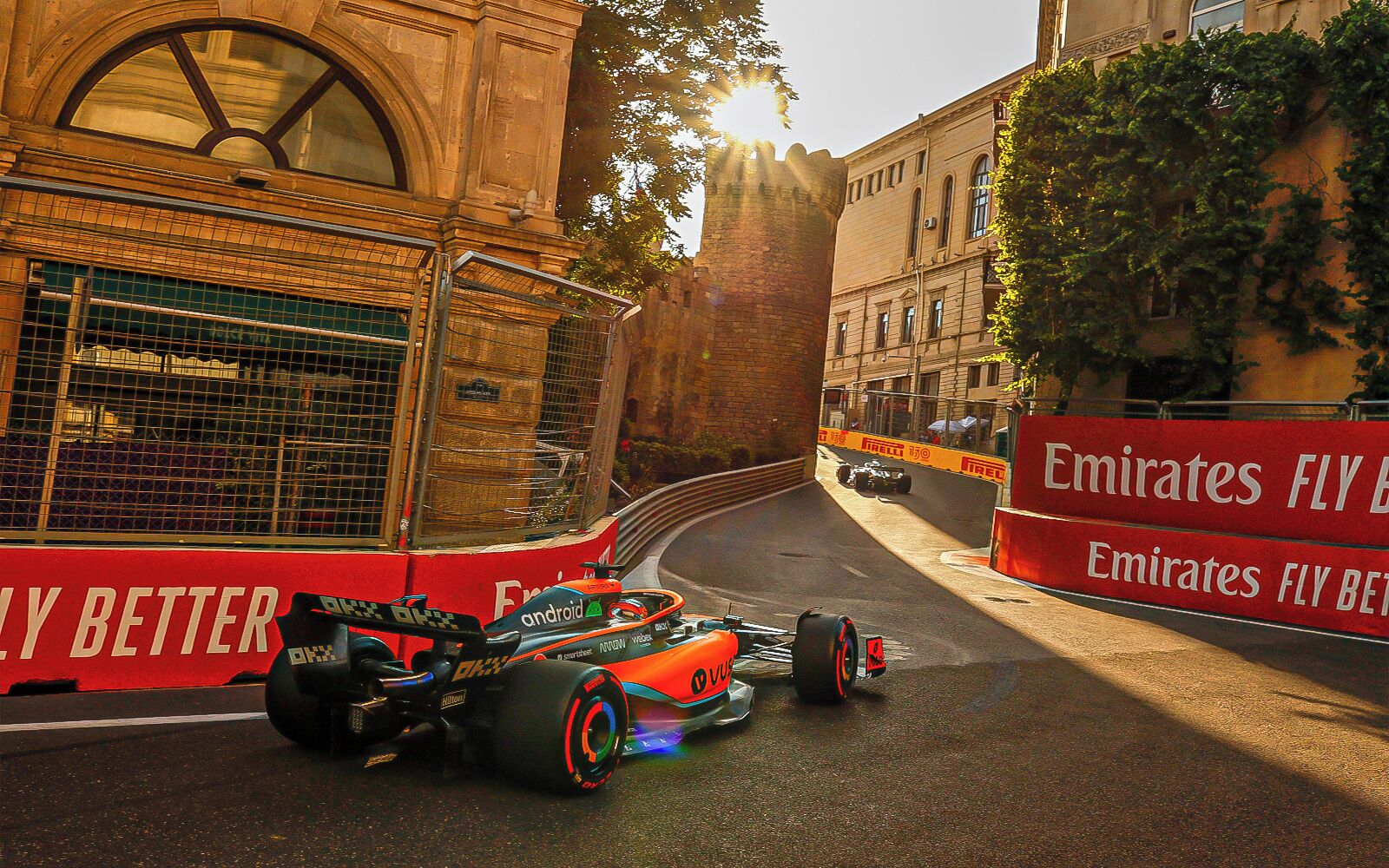 Une voiture de Formule 1 sur un circuit, avec une publicité rouge pour Emirates, dont le slogan est « Fly Better ».