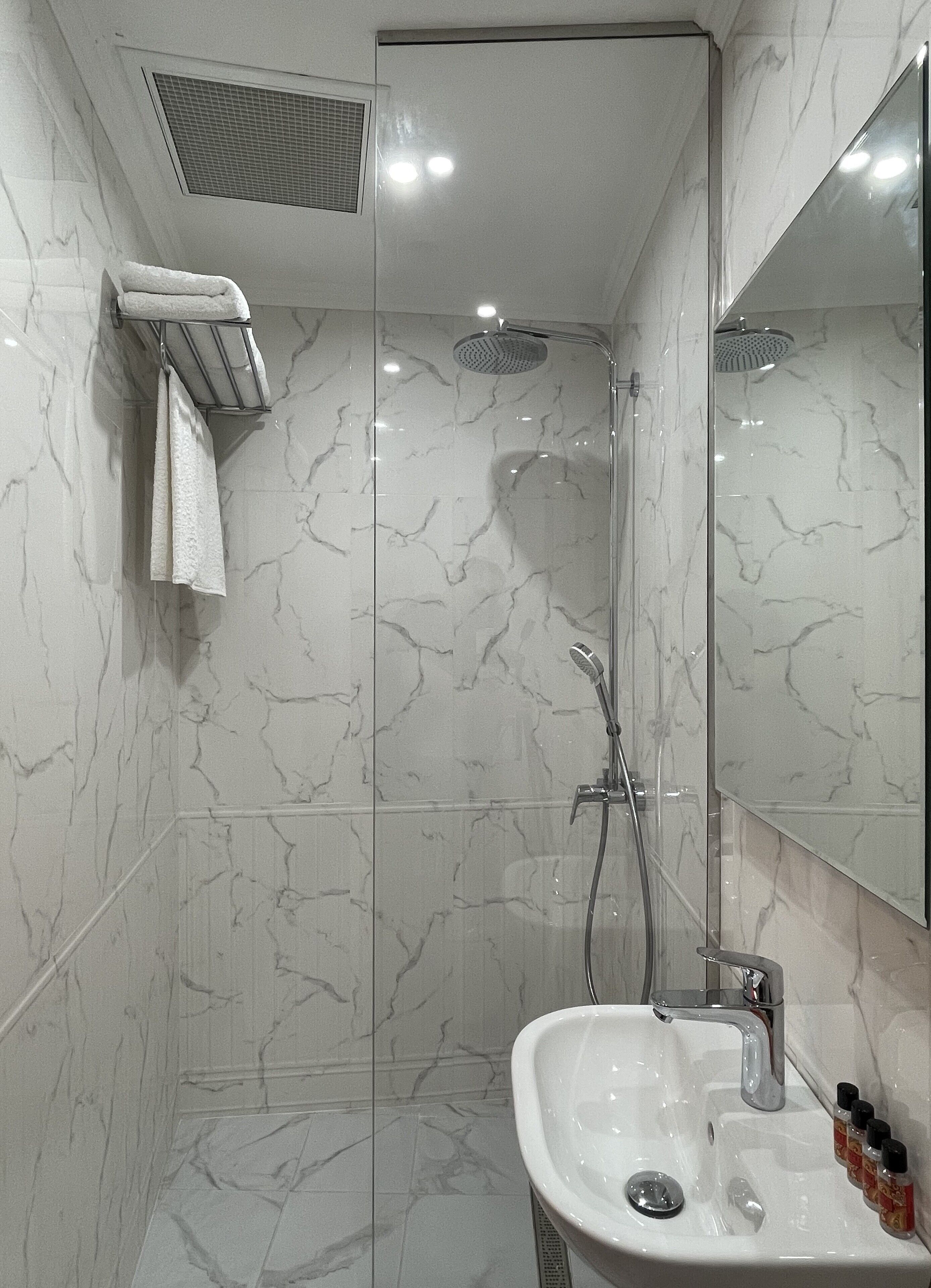 Un baño con ducha, lavamanos y espejo.