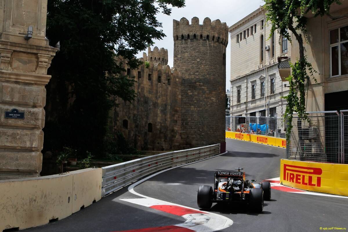 Une voiture de course sur une piste, avec une structure ressemblant à un château et un bâtiment portant une enseigne.