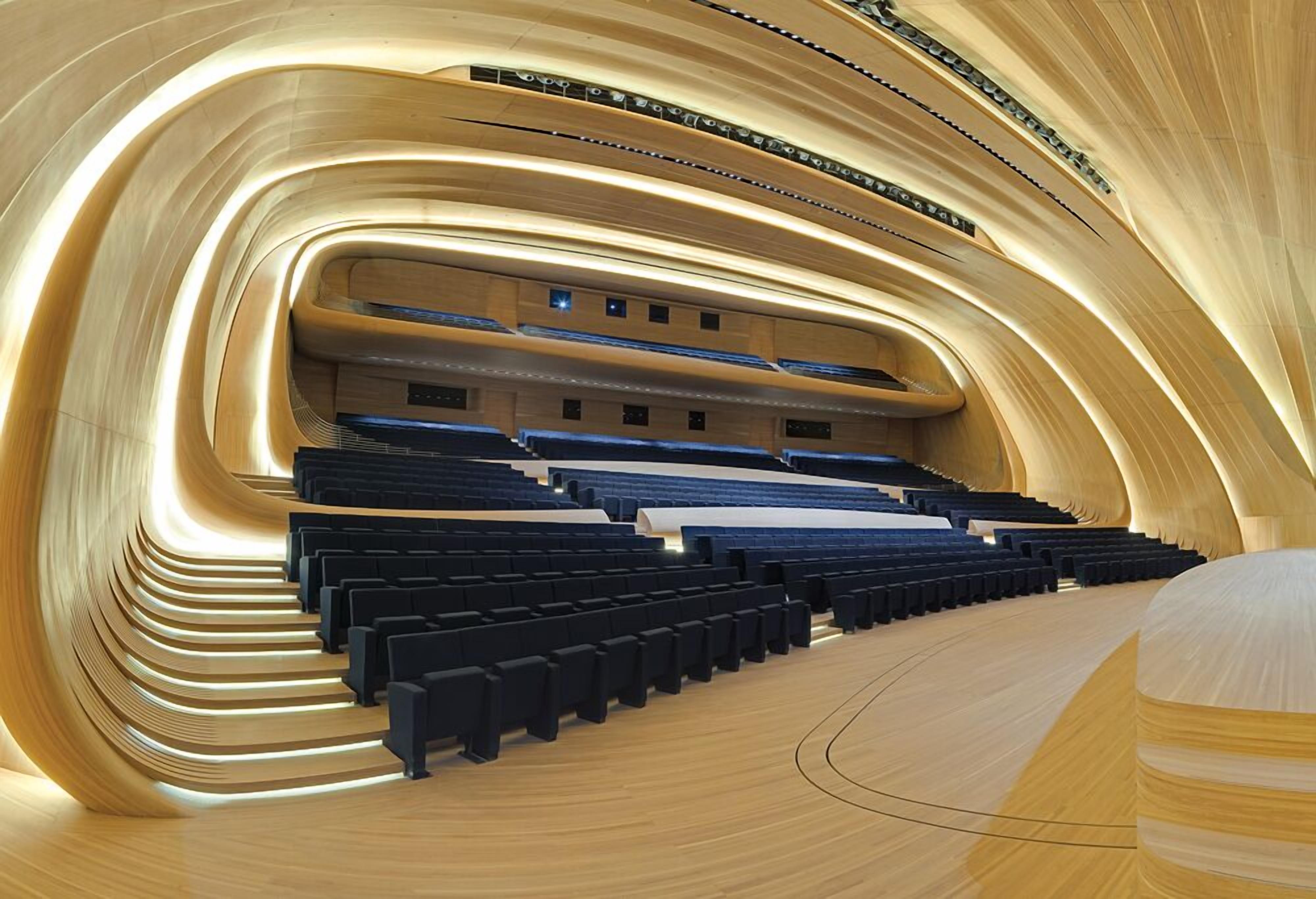 Un auditorium moderno con posti a gradinata e un design in legno curvo.