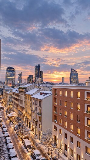 Paisatge urbà amb edificis moderns, un carrer cobert de neu i un capvespre.