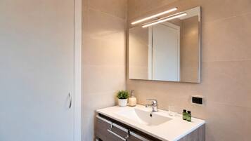 Un baño moderno con un espejo grande, un lavamanos y una planta en maceta.