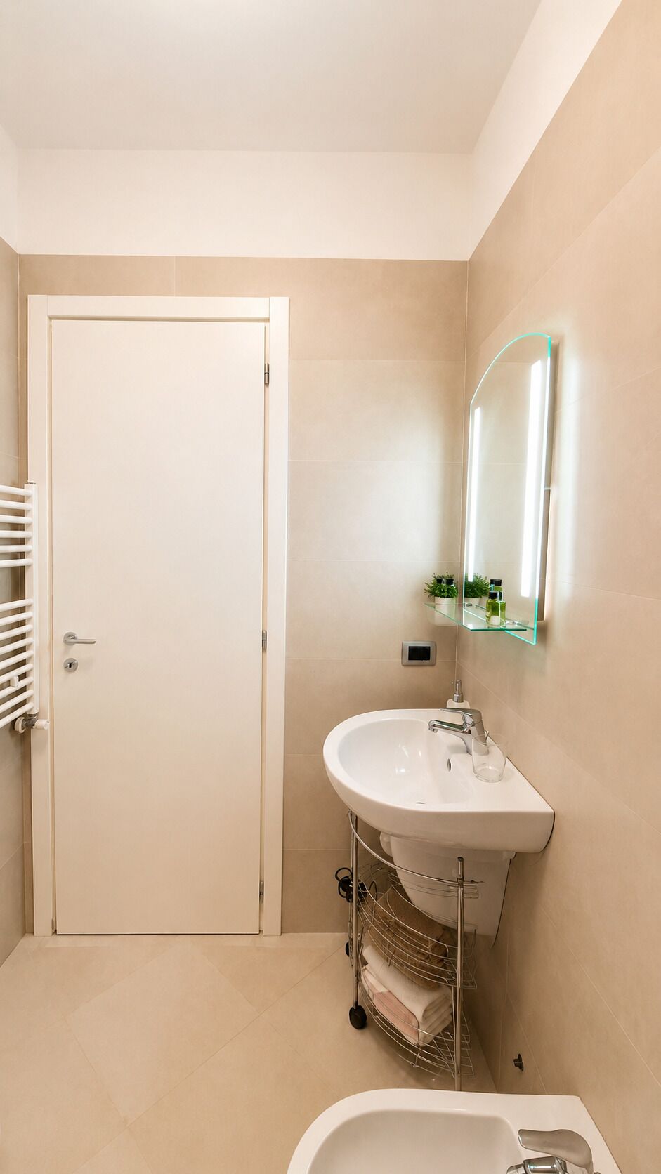 Ein Badezimmer mit weißer Tür, einem Waschbecken mit Spiegel und einem Handtuchhalter.