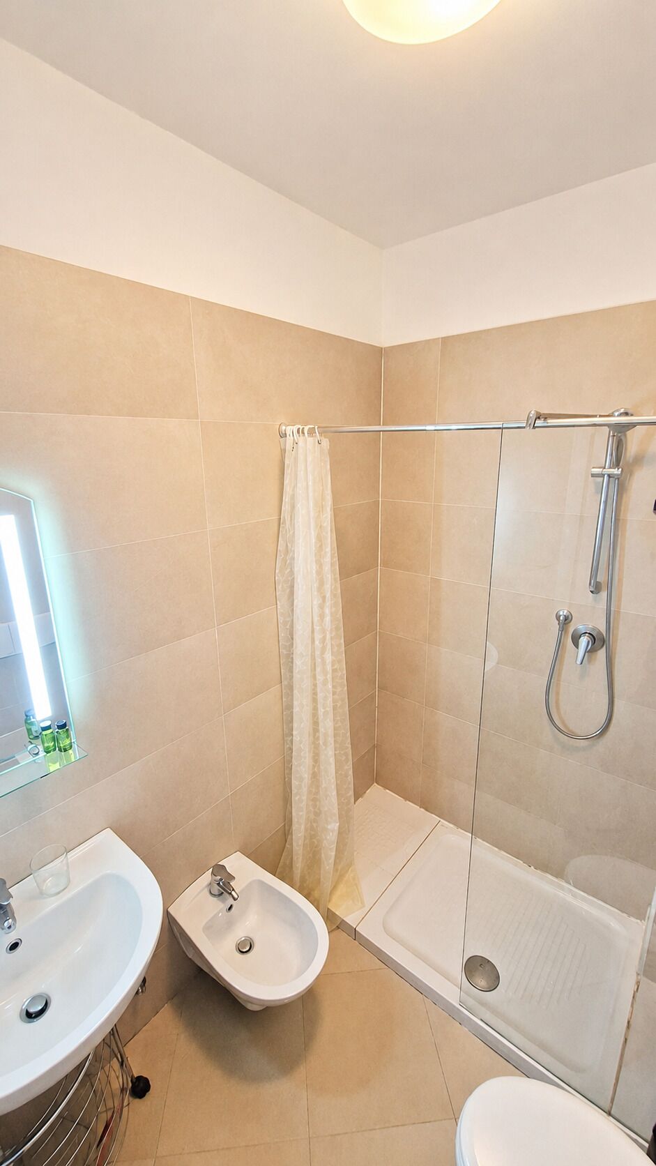 A bathroom with a shower, bidet, and sink.