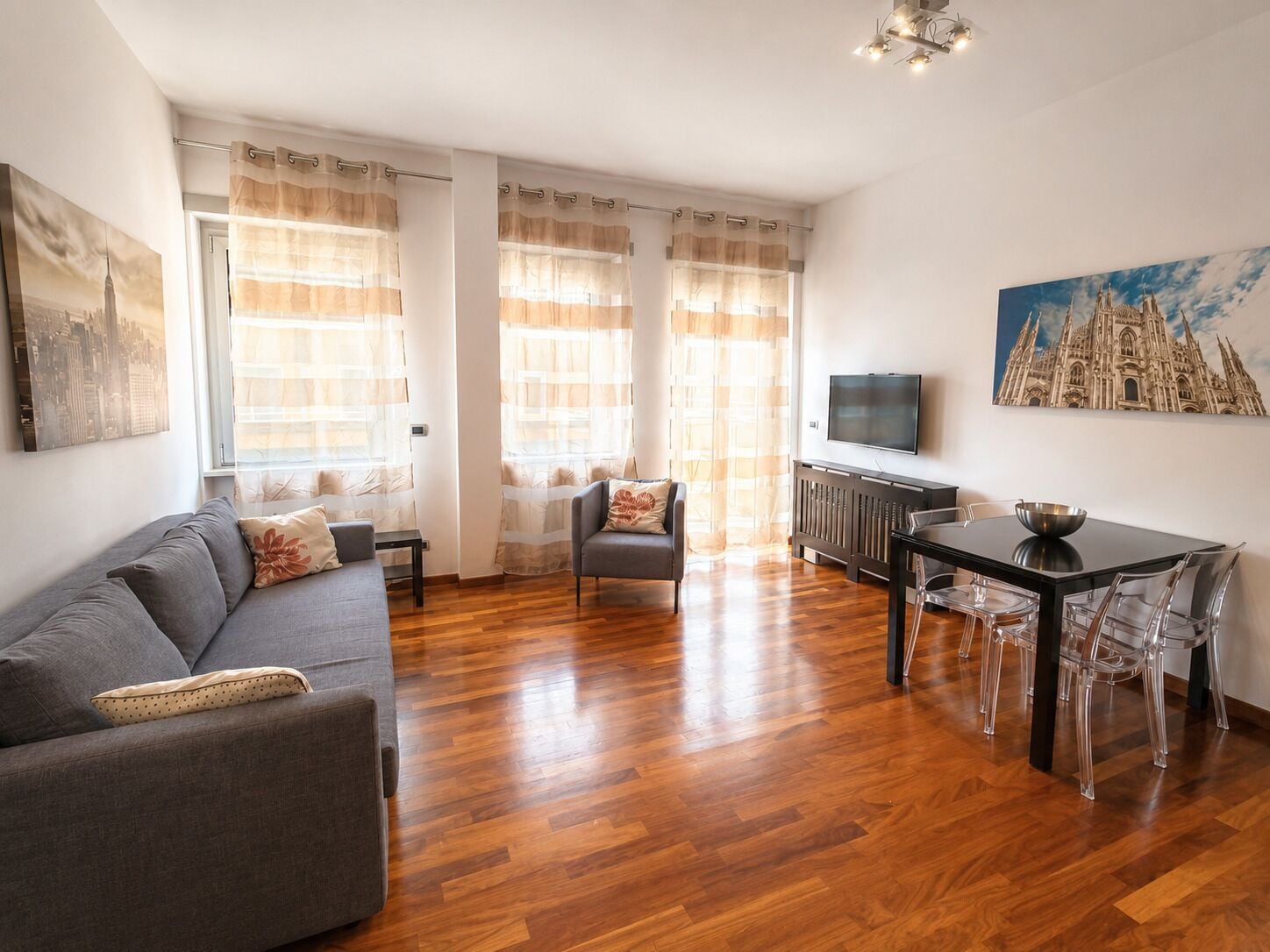 Un salon moderne comprenant un canapé, une table à manger, des chaises et un téléviseur.