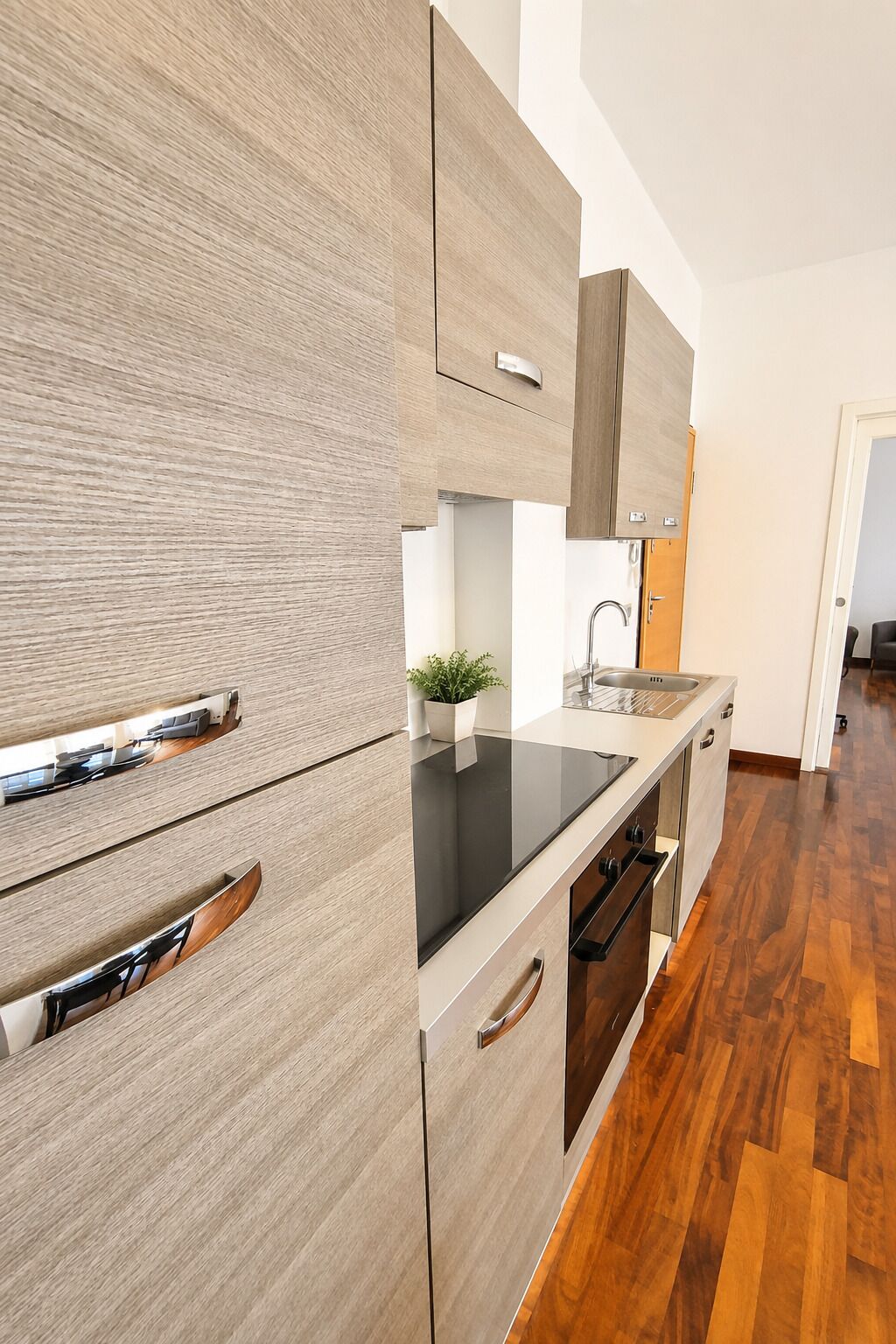 Une cuisine moderne avec des meubles de rangement en bois, un plan de travail noir et un four encastré.