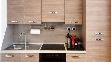 Una cocina moderna con armarios de madera, un lavamanos de acero inoxidable, horno empotrado y lavavajillas negro.