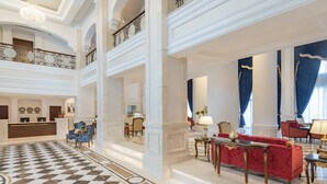 A grand lobby with a checkered floor, a reception desk, and a seating area with red sofas and a chandelier. - Riviera Rayhaan by Rotana Doha (Doha)