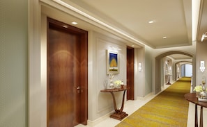 A hallway with wooden doors, a framed painting, and a small table with vases.
