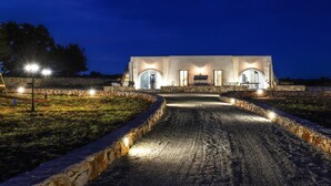 Un edificio moderno con un vialetto in pietra illuminato da luci a terra.