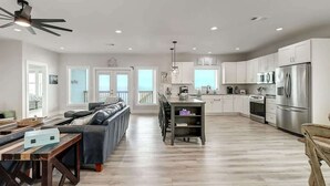 A spacious living area with a sofa, dining table, and kitchen with white cabinets and stainless steel appliances. - Soggy Pollards (Rockport)