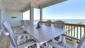 A covered outdoor dining area with a view of the ocean and pier. - Soggy Pollards (Rockport)