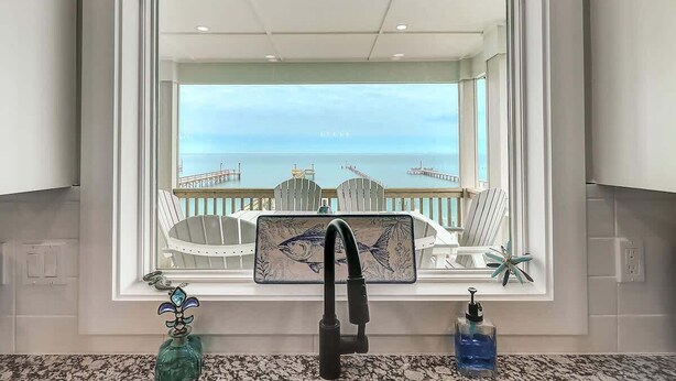 A bathroom with a large window, a sink, and a view of the sea. - Soggy Pollards (Rockport)