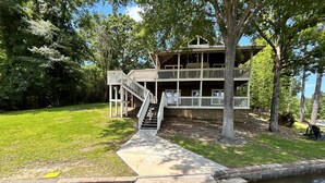 A wooden dock leading to a house with a porch and a staircase.