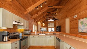 A kitchen with wooden beams, a large island, stainless steel appliances, and a map on the wall.