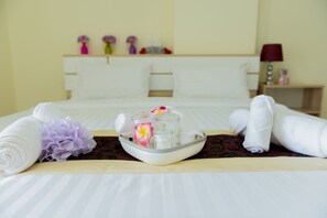 A neatly made bed with rolled towels, a tray with toiletries, and decorative flowers. - Be my guest36 (Bangkok)