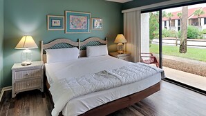 A bedroom with a large bed, two bedside tables with lamps, and three framed pictures on the wall.