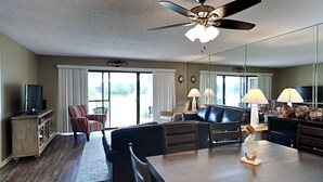 A spacious living area with a ceiling fan, a dining table, and a sofa.
