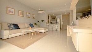 A modern living room with a sofa, coffee table, and a dining area with bar stools. - w* | Stunning 1BR with Pool in Cartagena (Cartagena de Indias)