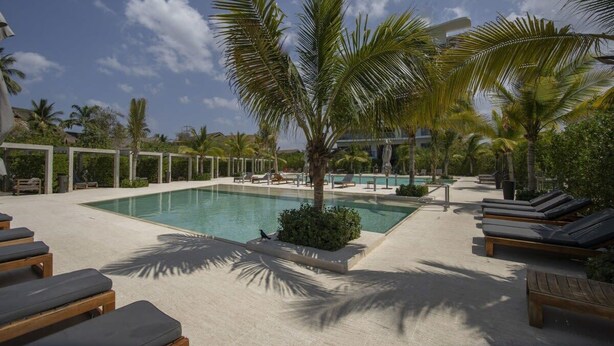 A pool area with lounge chairs, palm trees, and a clear sky. - w* | Stunning 1BR with Pool in Cartagena (Cartagena de Indias)