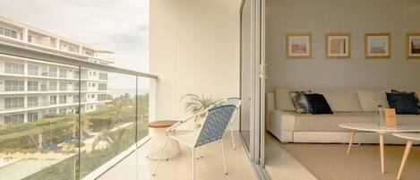 A modern living room with a balcony, a sofa, a coffee table, and a chair.