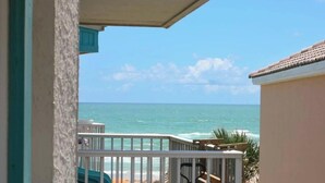 A balcony with a view of the ocean, a railing, and a partial view of a building.