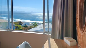 Una habitación con un amplio ventanal que ofrece vistas al océano y montañas distantes.
