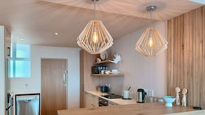 Una cocina moderna con armarios de madera, una isla central, luces colgantes y un microondas.