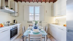 A compact kitchen with white cabinets, a built-in oven, and a window above the sink.