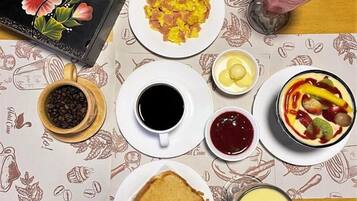 A breakfast table with coffee, scrambled eggs, toast, and a fruit salad.