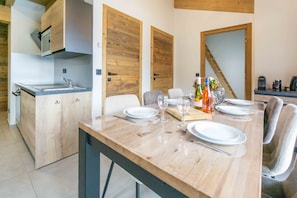 Une cuisine moderne avec des meubles en bois, une cuisinière encastrée et un coin repas avec une table en bois, mise pour quatre personnes.