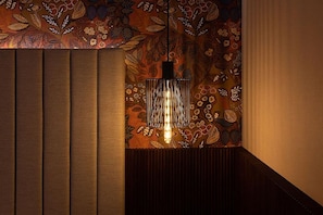 Un mur orné d’un motif floral et un luminaire suspendu.