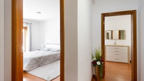 Une chambre à coucher avec un lit, une commode, un miroir et une plante en pot.