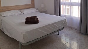 A hotel room with a bed, a bedside table, a lamp, and a window with curtains. - Holiday Home "Casa Rosi" with Mountain Views and Wi-Fi (Gran Tarajal)
