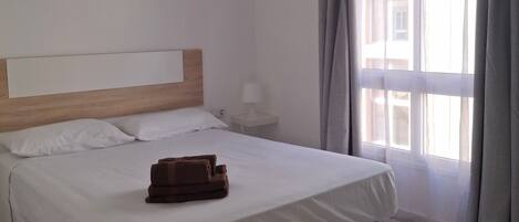 Ein Hotelzimmer mit einem Bett, einem Nachttisch, einer Lampe und einem Fenster mit Vorhängen.