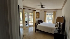 A bedroom with a bed, a nightstand, a ceiling fan, and a window with curtains.
