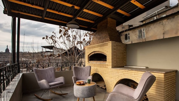 Una terrazza sul tetto con un forno a mattoni, due poltrone a dondolo e un tavolo rotondo.
