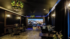 Un'elegante area relax con un grande schermo televisivo, sedute confortevoli e illuminazione decorativa.
